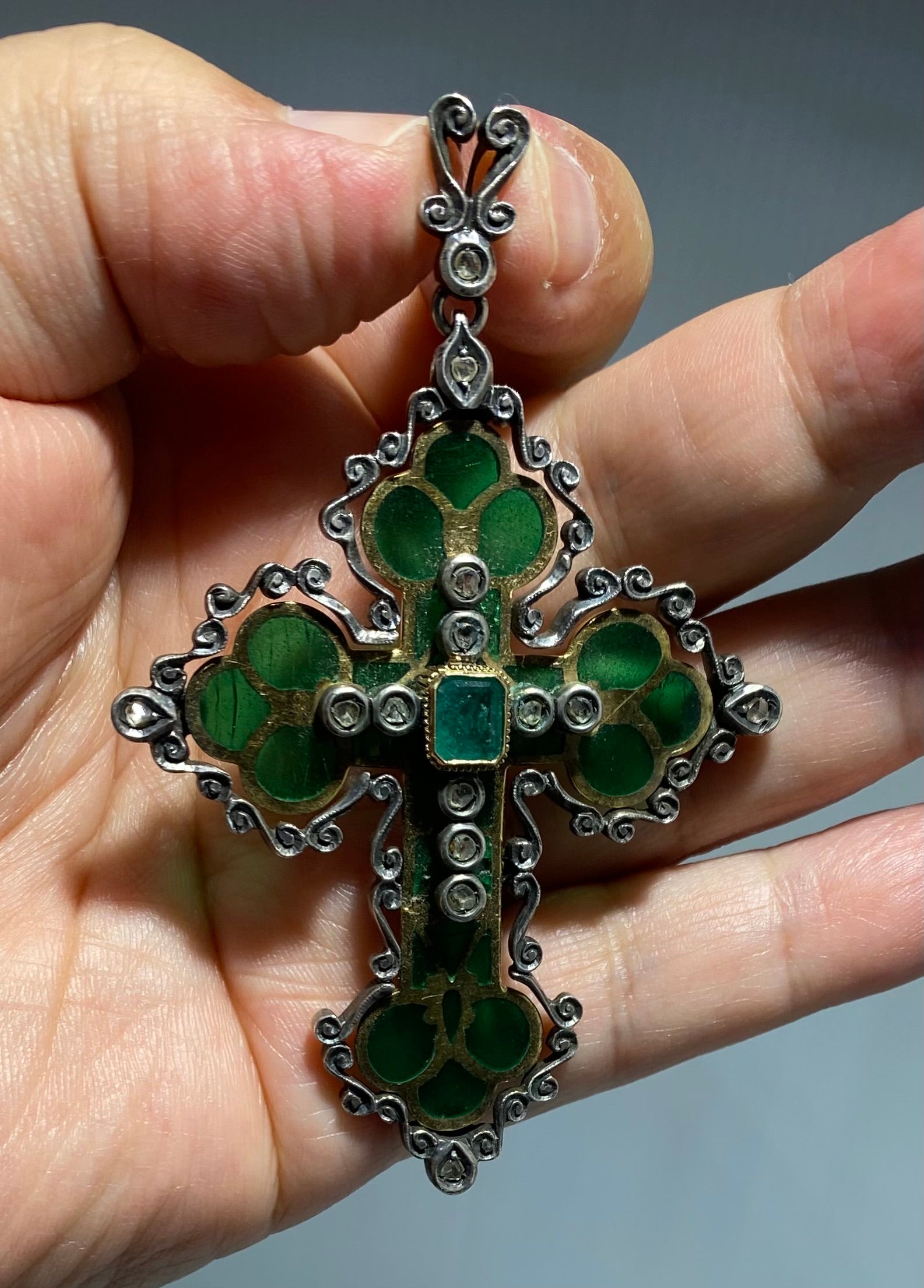 Antique silver and gold cross with inserts of green emeralds and diamonds.